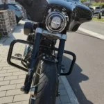 Vue de face de la Harley-Davidson mettant en valeur le grand phare avant rond à LED, la fourche inversée noire et les crash bars de protection.
