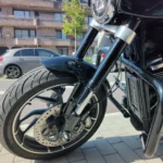 Gros plan sur la roue avant avec sa jante en alliage noir et argent, le pneu Dunlop, le disque de frein ventilé et le garde-boue noir brillant.