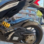 Gros plan sur l'amortisseur arrière réglable Öhlins jaune, la chaîne de transmission et la roue arrière d'une Ducati Multistrada 1260 Pikes Peak.