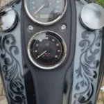 Vue rapprochée du compteur de vitesse analogique chromé et des rehausses de guidon d'une Harley-Davidson