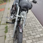 Vue de face d'une Harley-Davidson Dyna Low Rider équipée d'une sacoche de guidon en cuir, d'un phare rond et d'une roue à rayons.