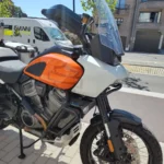 Vue trois-quarts avant d'une Harley-Davidson Pan America 1250 montrant la bulle haute, les crash-bars et la roue à rayons.