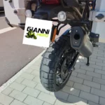 Profil latéral gauche d'une Harley-Davidson Pan America 1250 orange et blanche garée sur béquille centrale.