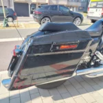 Zoom sur la valise rigide latérale droite noire d'une Harley-Davidson Street Glide avec détails de pinstriping et feux arrière chromés.