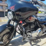 Vue rapprochée sous un angle trois-quarts avant d'une Harley-Davidson Street Glide 96ci noire avec tête de fourche Batwing, phare LED et motif pinstriping rouge.